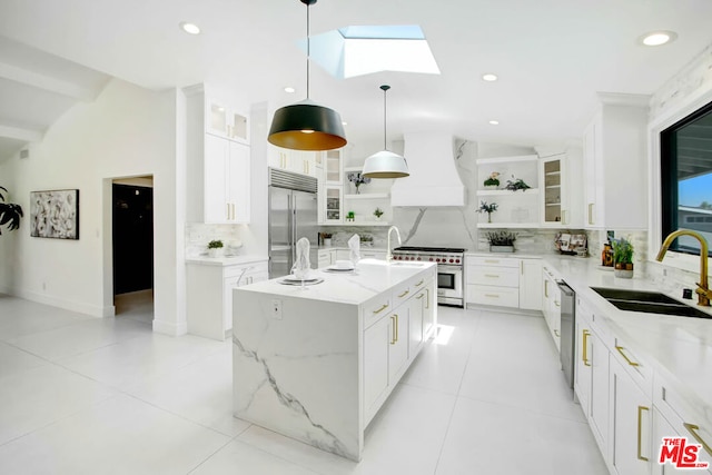 kitchen featuring white cabinets, high quality appliances, premium range hood, and a kitchen island with sink