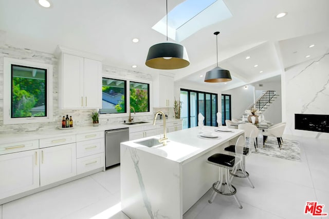 kitchen featuring stainless steel dishwasher, decorative light fixtures, white cabinets, and a skylight