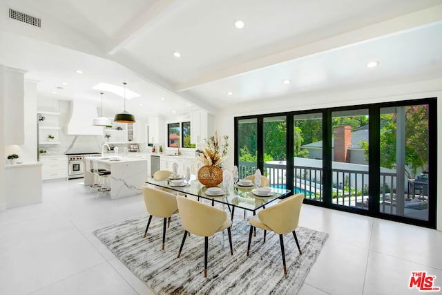 dining space featuring sink, light tile patterned floors, and lofted ceiling with beams