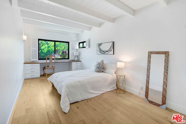 bedroom featuring lofted ceiling with beams, light hardwood / wood-style floors, and built in desk