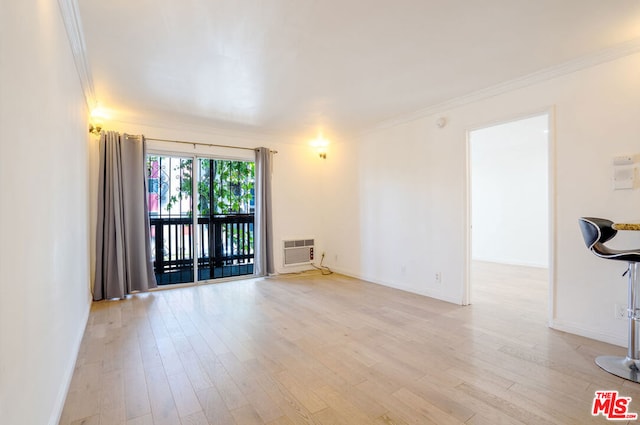 empty room featuring light hardwood / wood-style floors, crown molding, and an AC wall unit