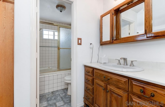 full bathroom featuring vanity, tiled shower / bath combo, and toilet