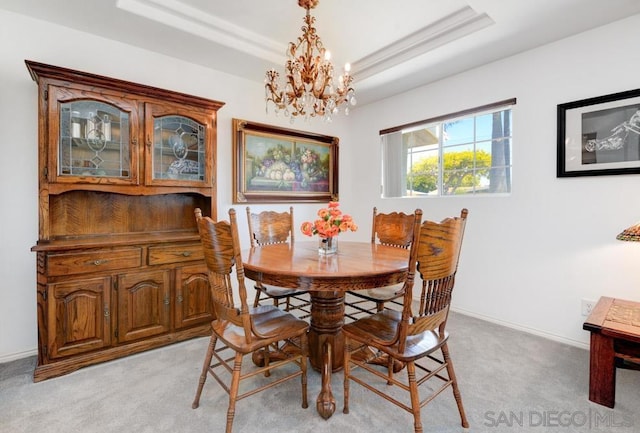 dining room featuring light colored carpet, a tray ceiling, and a chandelier