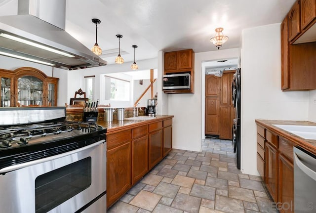 kitchen featuring island range hood, decorative light fixtures, appliances with stainless steel finishes, and sink