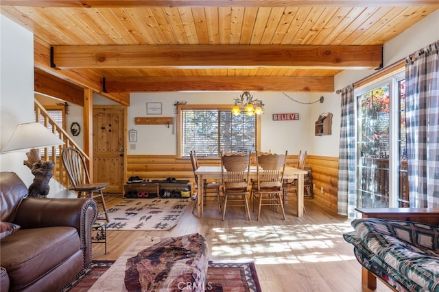 dining area featuring rustic walls, beamed ceiling, light hardwood / wood-style floors, and wood ceiling