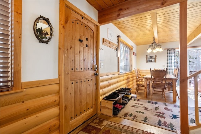 foyer with wooden ceiling, vaulted ceiling with beams, rustic walls, and a chandelier