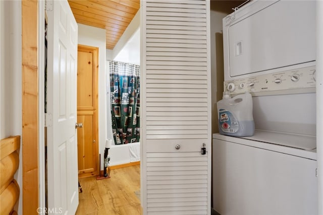 clothes washing area with light hardwood / wood-style floors, stacked washing maching and dryer, and wood ceiling