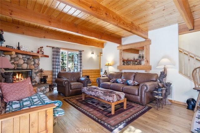 living room with beamed ceiling, wooden ceiling, a stone fireplace, and hardwood / wood-style flooring