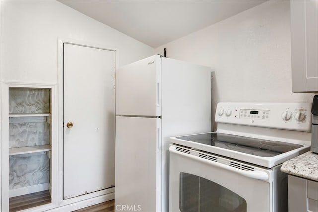 kitchen featuring lofted ceiling and white appliances