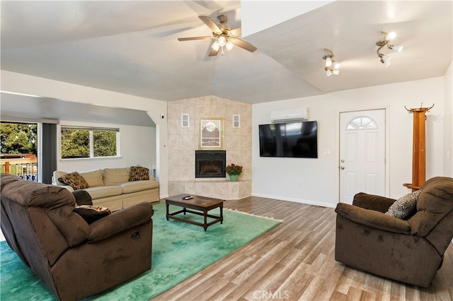 living room with a fireplace, hardwood / wood-style flooring, a wall mounted air conditioner, and ceiling fan