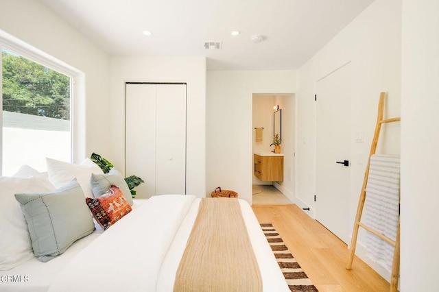 bedroom featuring light wood-type flooring, a closet, and connected bathroom