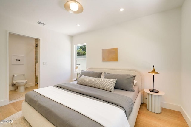 bedroom featuring connected bathroom and light hardwood / wood-style floors