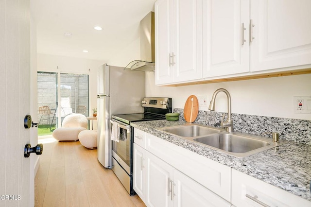 kitchen featuring sink, light hardwood / wood-style flooring, wall chimney exhaust hood, white cabinetry, and electric range