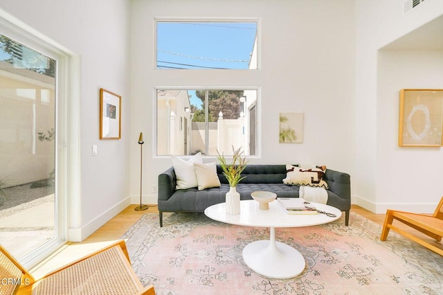 living room with a towering ceiling and light wood-type flooring