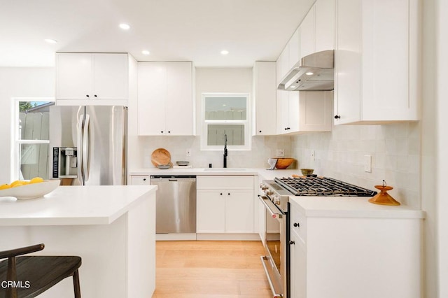 kitchen featuring stainless steel appliances, sink, a breakfast bar, and white cabinetry