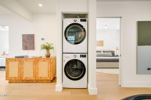 clothes washing area with stacked washer / dryer and hardwood / wood-style floors