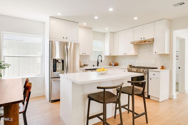 kitchen featuring light hardwood / wood-style floors, white cabinets, appliances with stainless steel finishes, and a center island