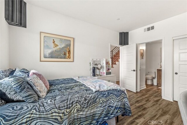 bedroom with wood-type flooring and ensuite bath