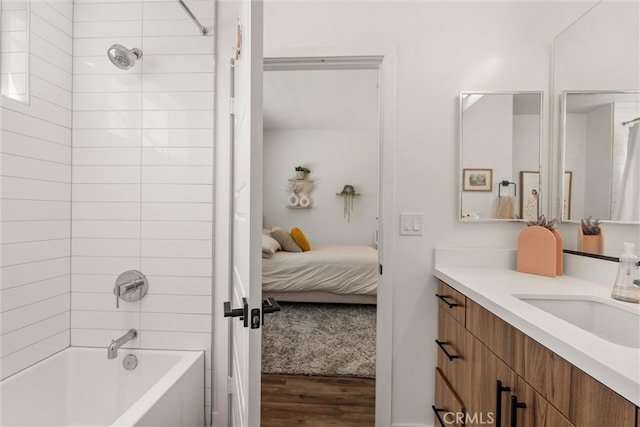 bathroom with tiled shower / bath combo, wood-type flooring, and vanity