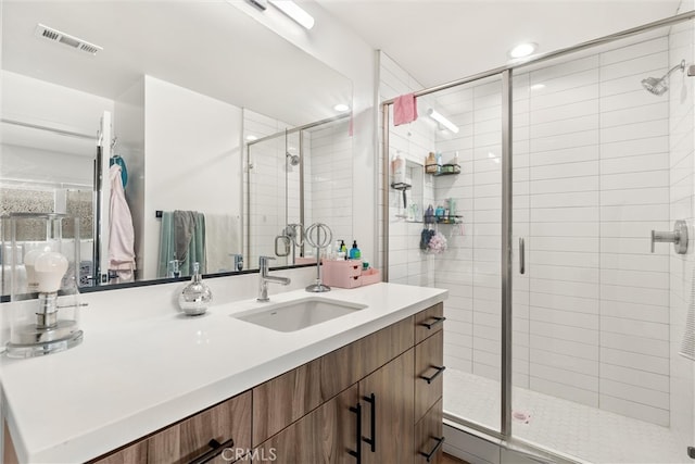 bathroom featuring a shower with shower door and vanity