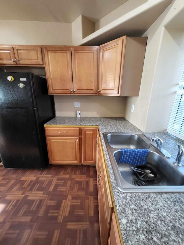 kitchen with dark parquet floors, black fridge, and sink