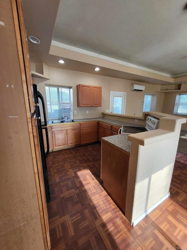 kitchen with a tray ceiling, white stove, kitchen peninsula, a kitchen bar, and light brown cabinetry