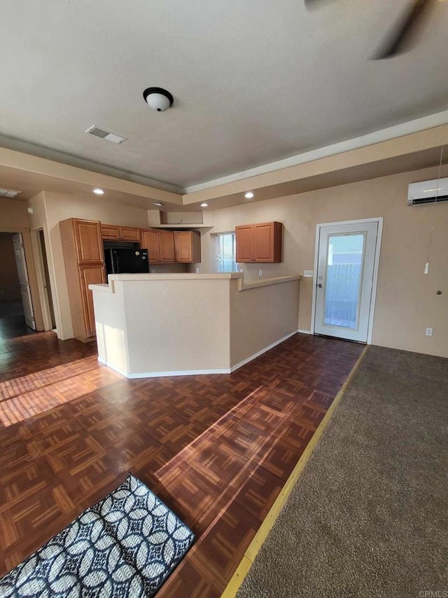 kitchen with kitchen peninsula, an AC wall unit, and black fridge