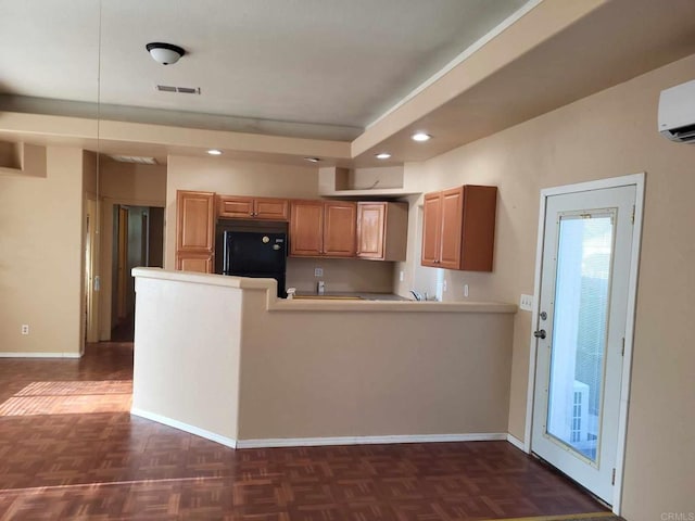 kitchen featuring kitchen peninsula, black fridge, a wall mounted air conditioner, and dark parquet flooring