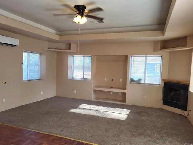 unfurnished living room featuring ceiling fan, a raised ceiling, carpet flooring, and a wealth of natural light