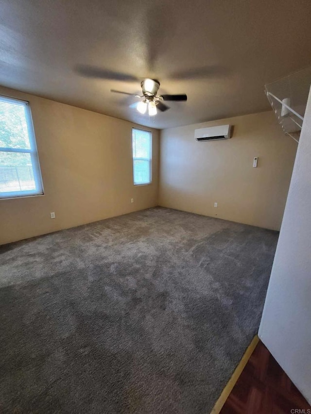 empty room with dark carpet, ceiling fan, and a wall unit AC