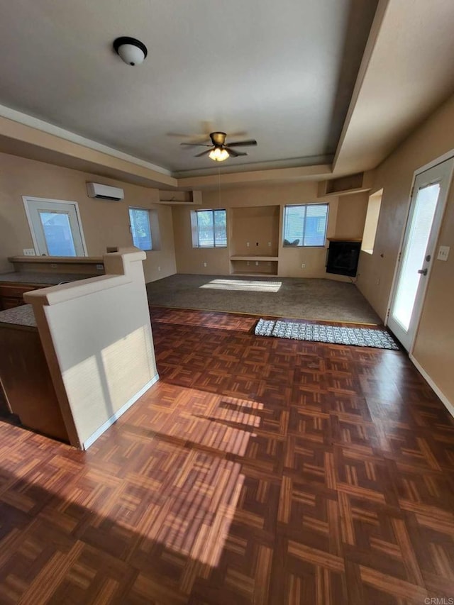 kitchen with an AC wall unit, a tray ceiling, and ceiling fan