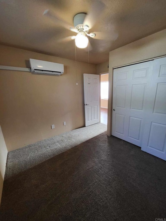 unfurnished bedroom with a closet, a textured ceiling, dark carpet, ceiling fan, and a wall mounted air conditioner