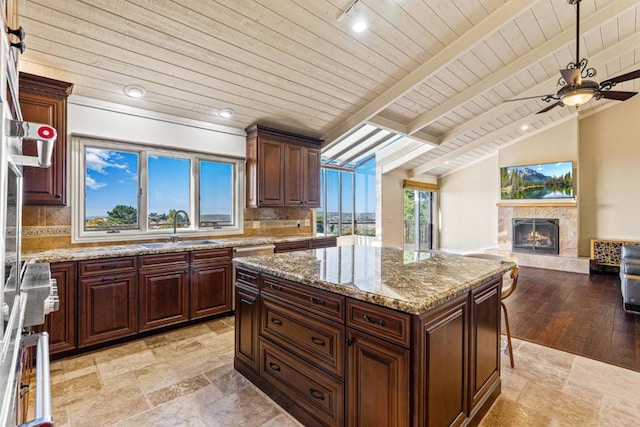 kitchen with tasteful backsplash, light stone countertops, sink, and a kitchen island