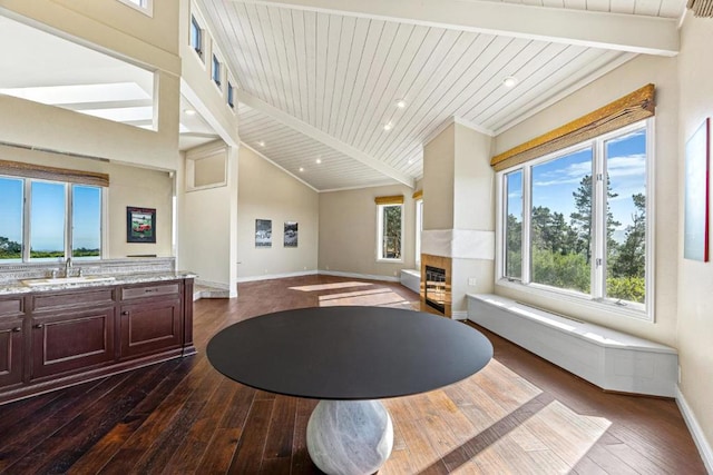 living room featuring sink, vaulted ceiling with beams, wooden ceiling, dark hardwood / wood-style floors, and a tile fireplace