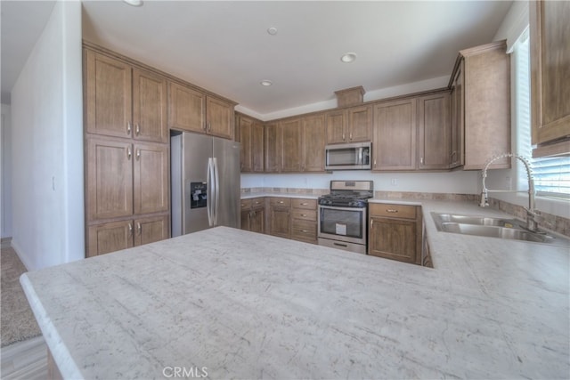 kitchen featuring sink, stainless steel appliances, kitchen peninsula, and light stone counters