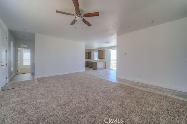 unfurnished living room featuring ceiling fan and light carpet