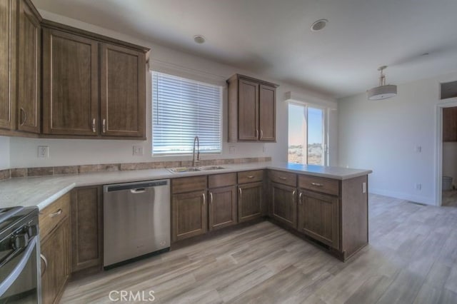 kitchen with light hardwood / wood-style floors, dishwasher, sink, kitchen peninsula, and stove