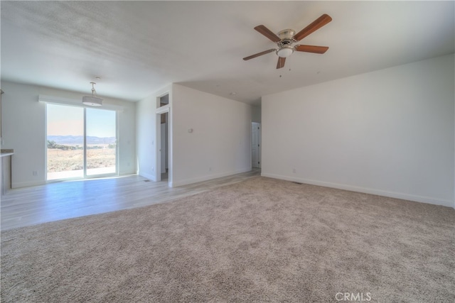 unfurnished living room with light colored carpet and ceiling fan