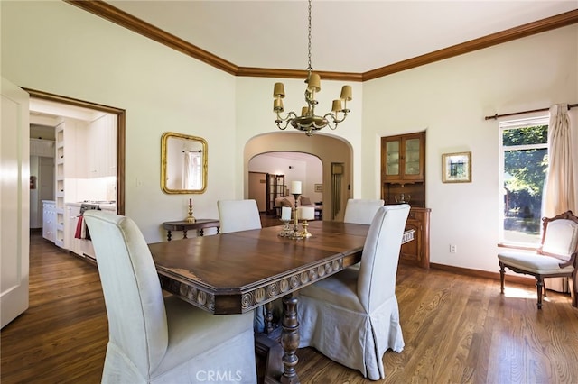 dining space with crown molding, dark wood-type flooring, and an inviting chandelier