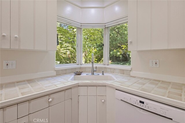 kitchen with dishwasher, tile countertops, a wealth of natural light, sink, and white cabinetry