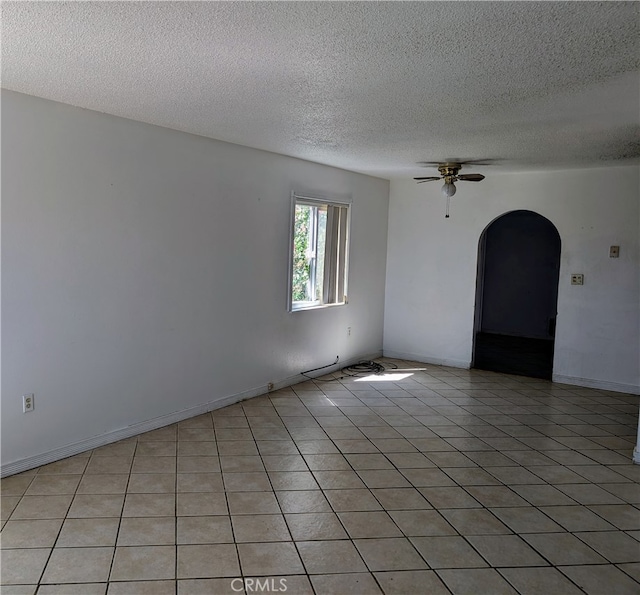 tiled spare room with a textured ceiling and ceiling fan