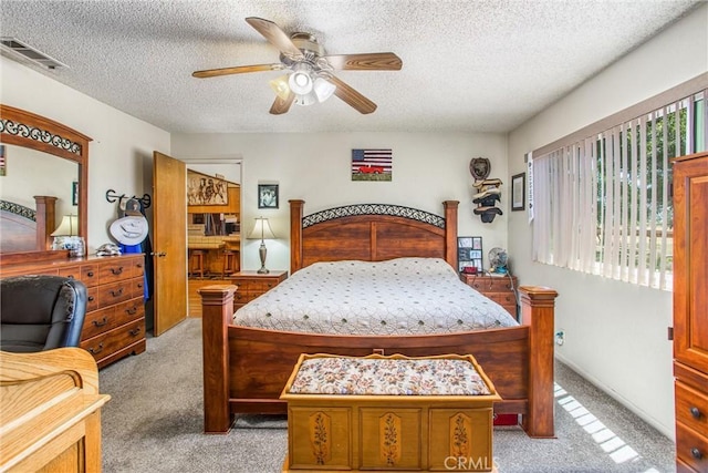 bedroom featuring visible vents, ceiling fan, light carpet, and a textured ceiling