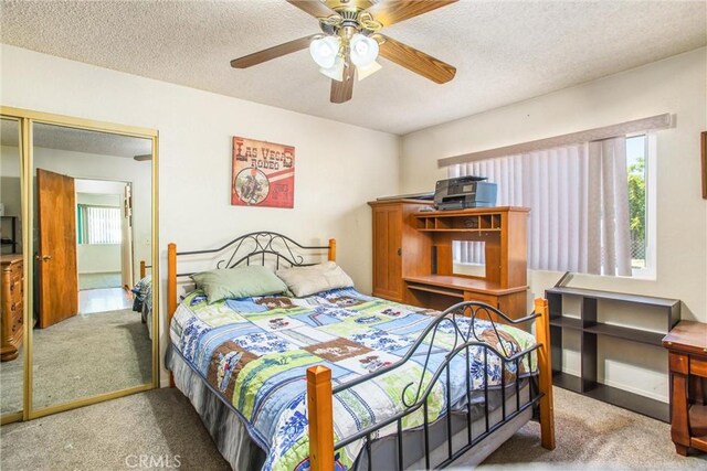 carpeted bedroom with ceiling fan, a textured ceiling, and a closet