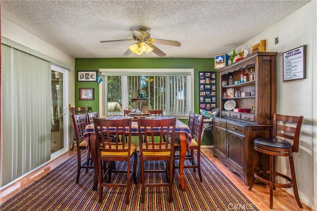 dining area with light wood finished floors, a textured ceiling, baseboards, and a ceiling fan