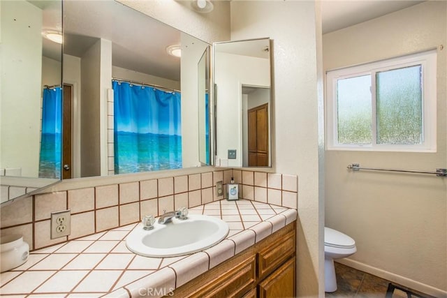 bathroom featuring toilet, baseboards, backsplash, and vanity