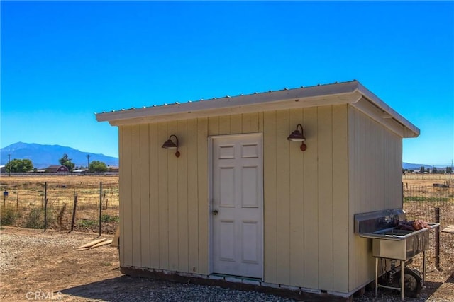 view of shed featuring a rural view, fence, and a mountain view