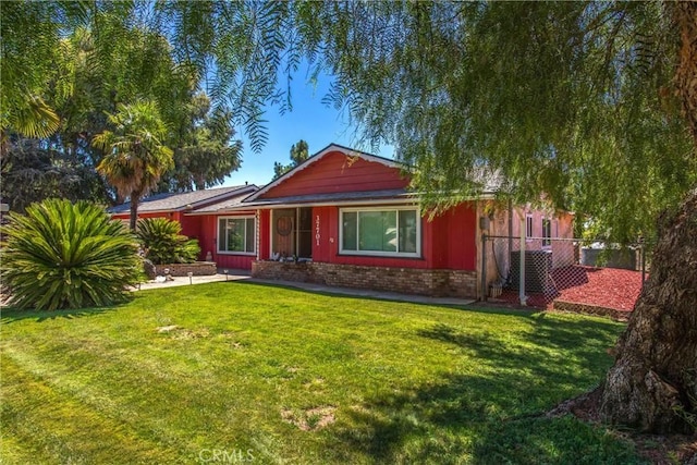 ranch-style house featuring brick siding, fence, and a front lawn