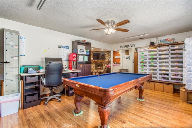 rec room with a textured ceiling, ceiling fan, light hardwood / wood-style floors, and pool table