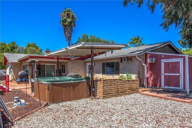 view of front of home featuring a storage shed, stucco siding, an outbuilding, and a hot tub