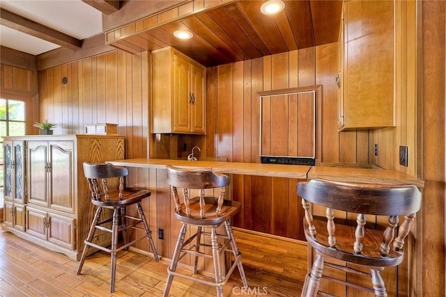 bar with recessed lighting, wood walls, a sink, light wood finished floors, and beamed ceiling